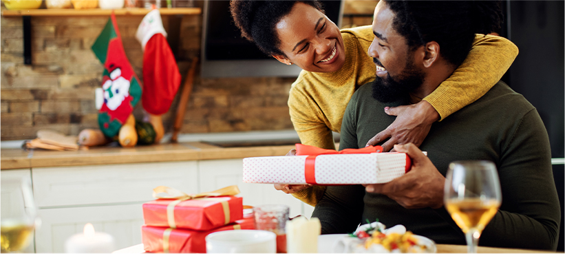 Woman giving husband gift at holiday dinner.
